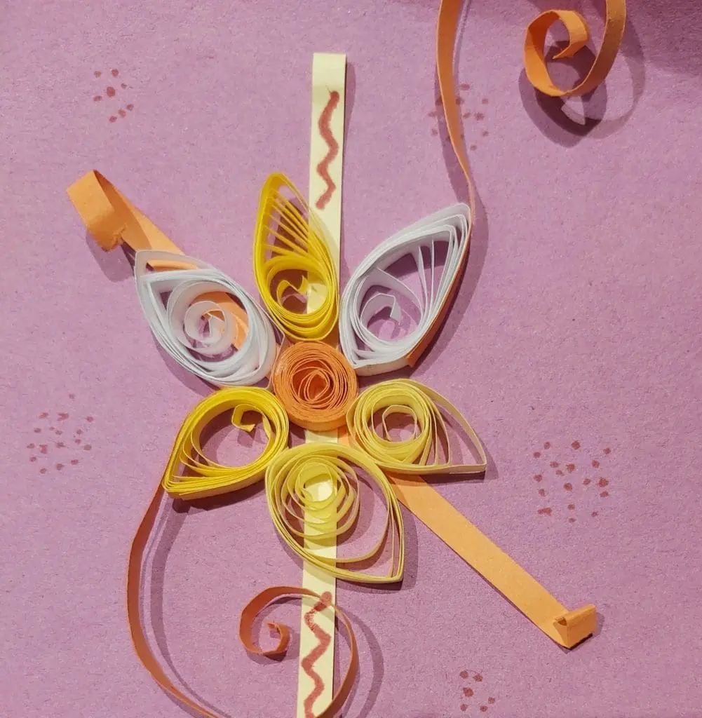 A purple background with yellow and orange paper flowers.