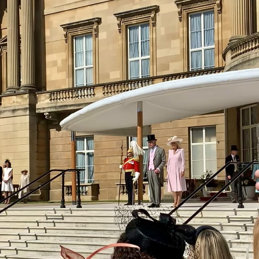 Royal couple on palace steps with guard.