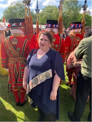 Woman in blue dress with guards in red.