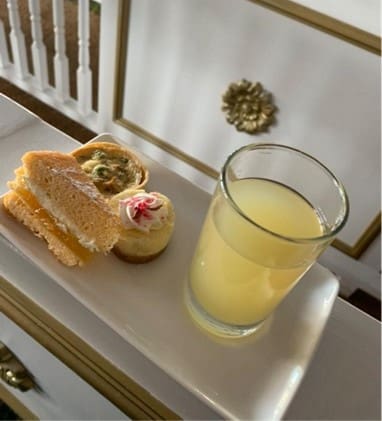 A glass of juice and pastries on a plate.