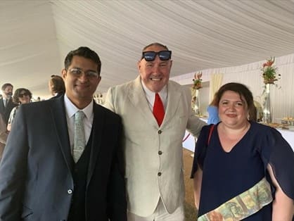 Three men in a white tent smiling.