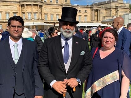 Three people posing in front of a palace.