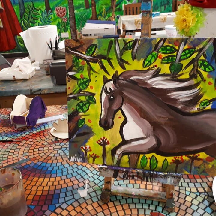 A painting of a horse on canvas with easel.