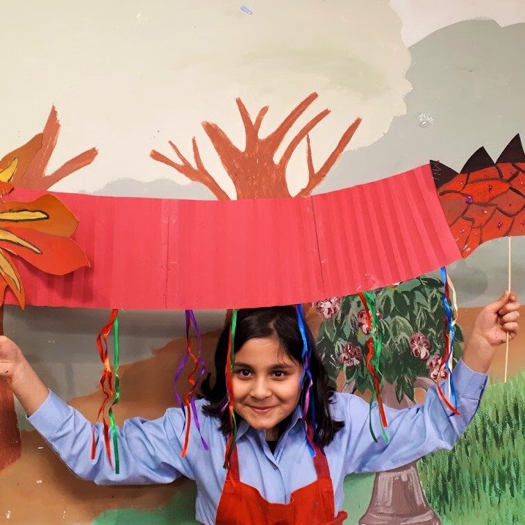 A girl holding up an umbrella made of paper.