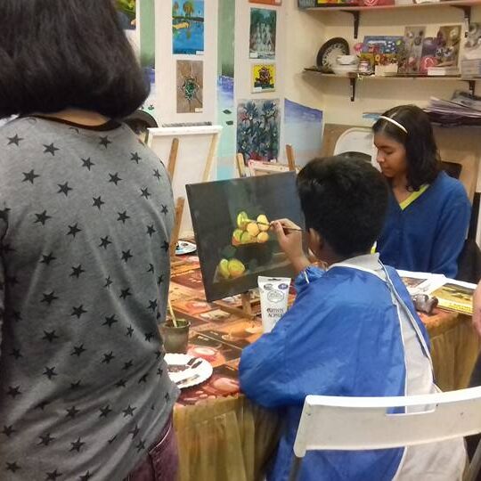 A group of people sitting around a table with paintings.